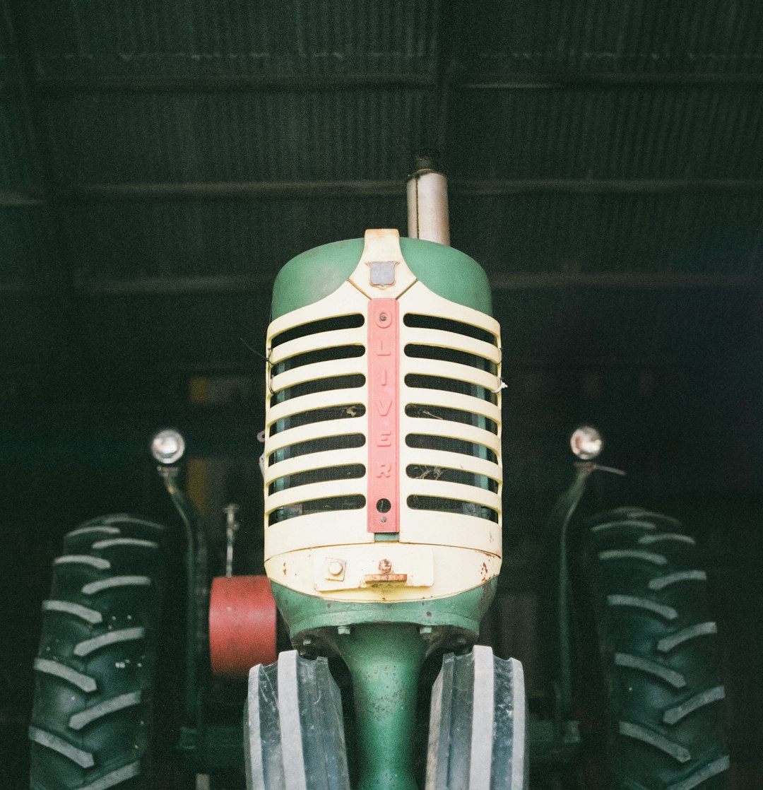 Zöld vintage traktor frontnézete, fehér és fekete csíkozással, piros gombokkal a középső panel központján