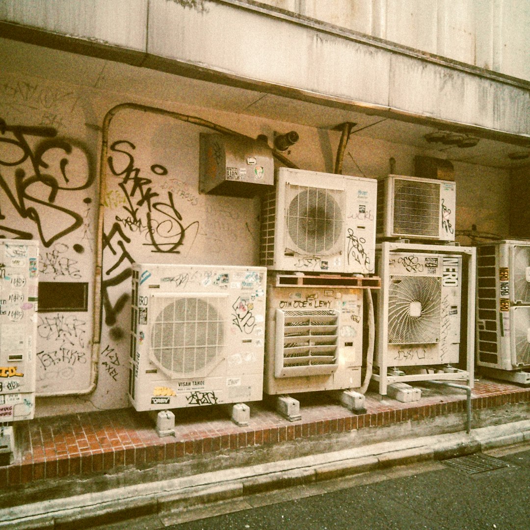 Rosszul elhelyezett kültéri klímaegység graffitikkel fedett épület falán, szűkös térbe szorítva